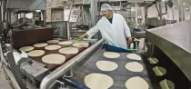 Man Manufacturing Hand-Stretched Tortillas On A Machine